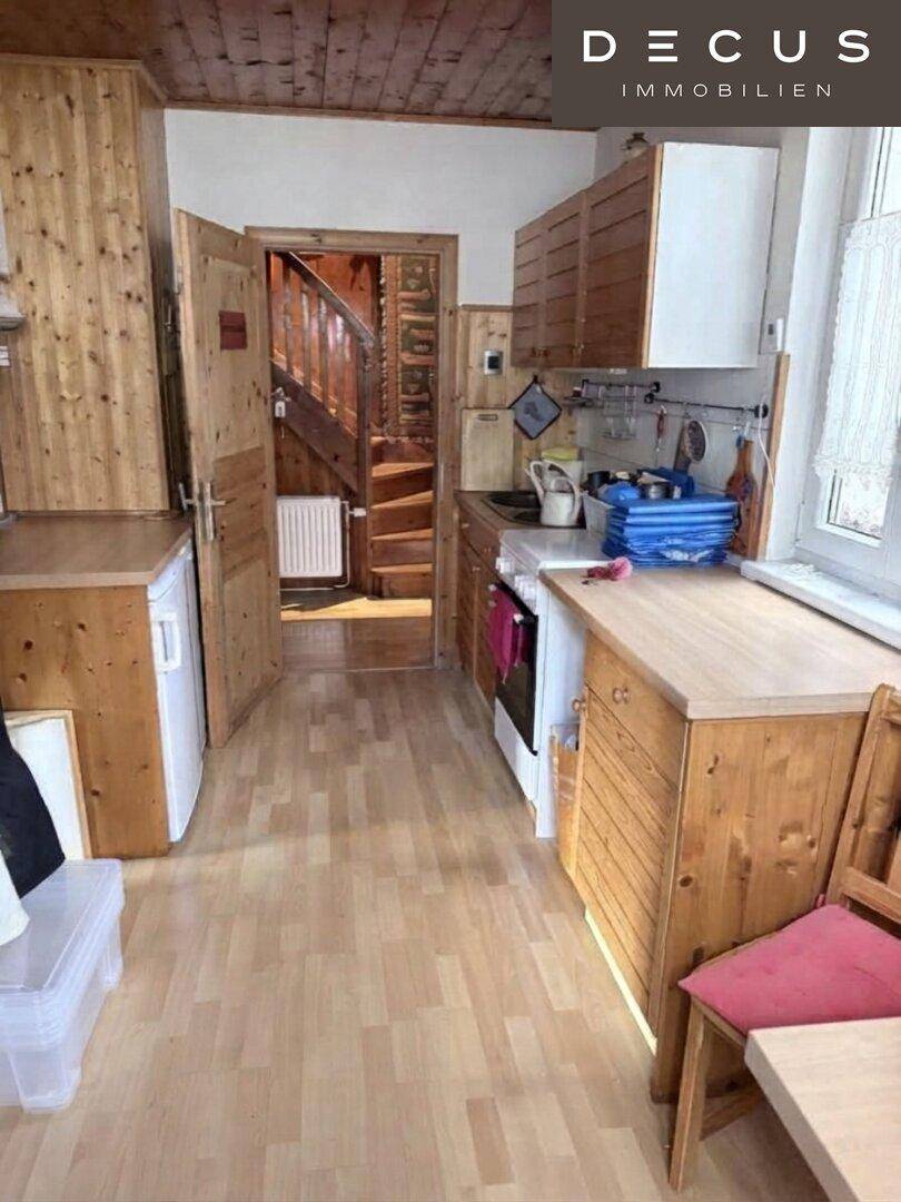 Funktionale Küche mit Holzfronten und direktem Zugang zum Treppenhaus.
