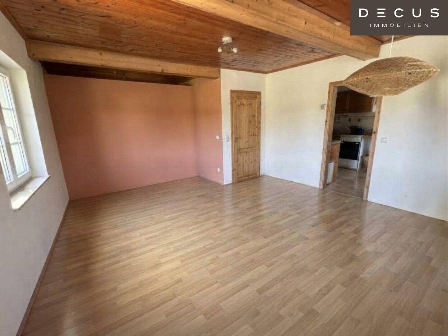Geräumiges Wohnzimmer mit Holzbalkendecke und Laminatboden, bereit zur individuellen Gestaltung.