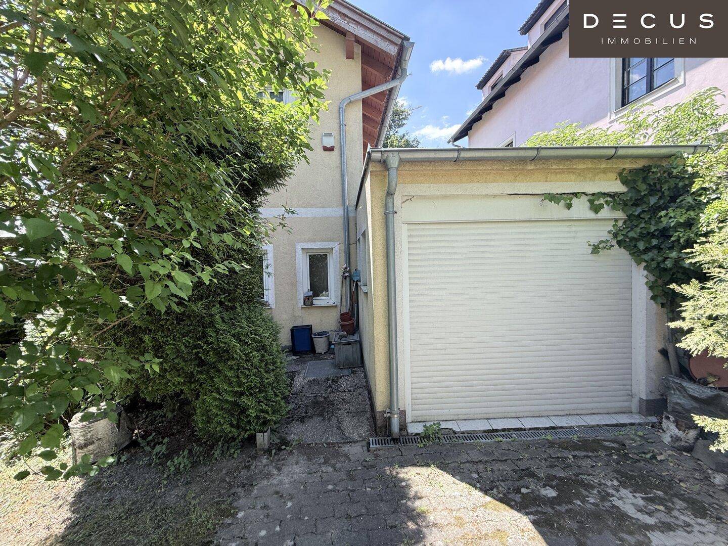 Seitenansicht des Hauses mit einer Einzelgarage und dichtem Bewuchs.