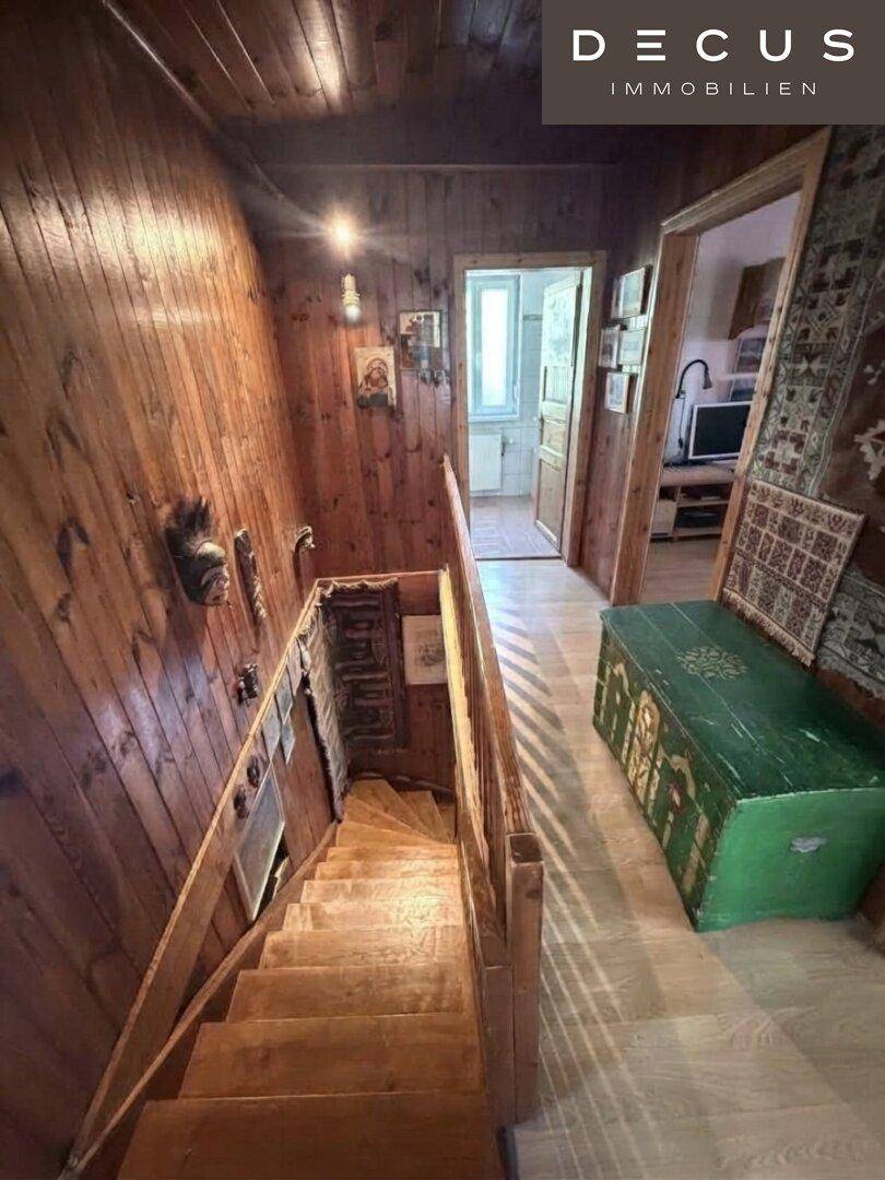 Holztreppe führt in den unteren Bereich, umgeben von rustikaler Holzvertäfelung.