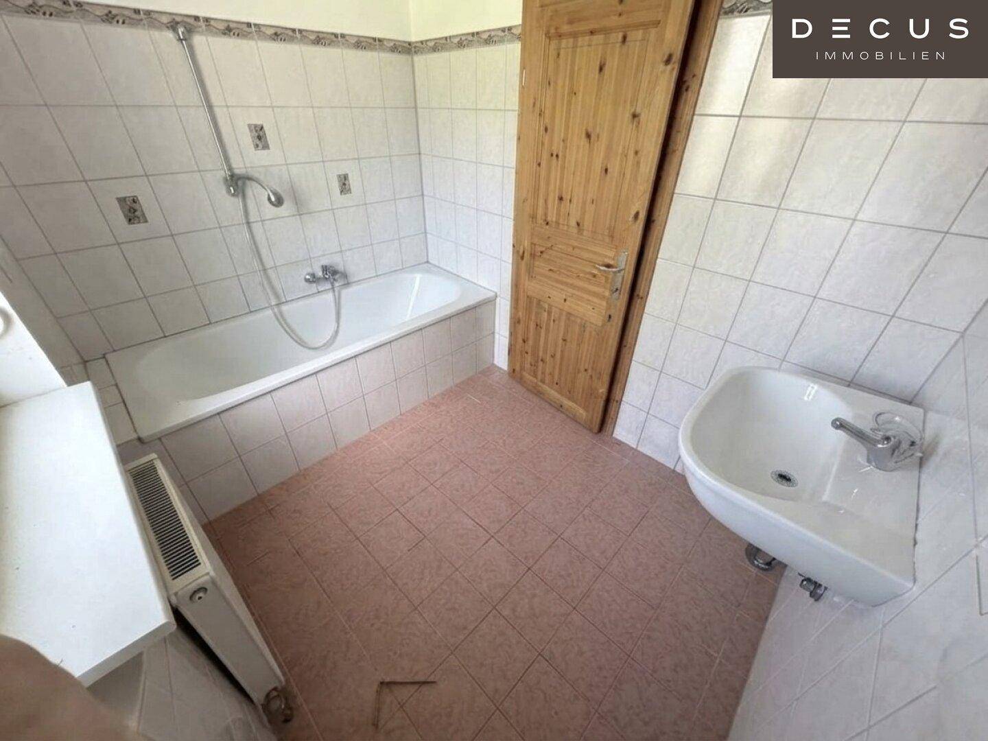 Badezimmer mit Badewanne, Waschbecken und Fliesenboden, bietet grundlegenden Komfort.