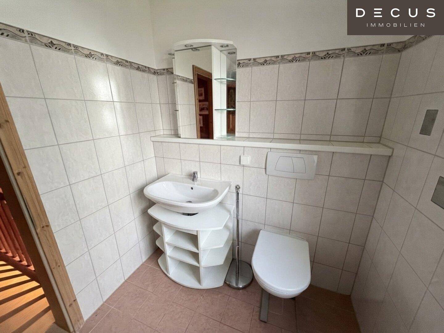 Separate Gästetoilette mit Waschbecken und Wand-WC, gefliest und funktional.