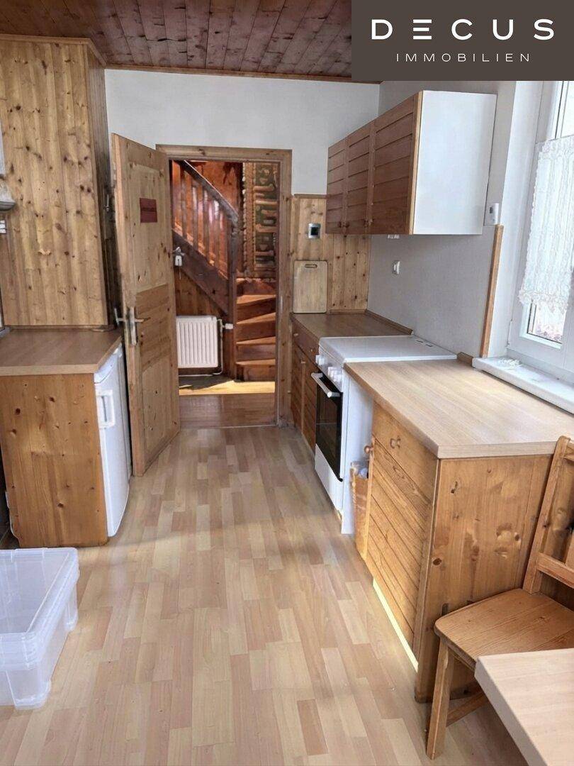 Rustikale Küche mit Holzvertäfelung, Laminatboden und Blick auf eine Holztreppe.