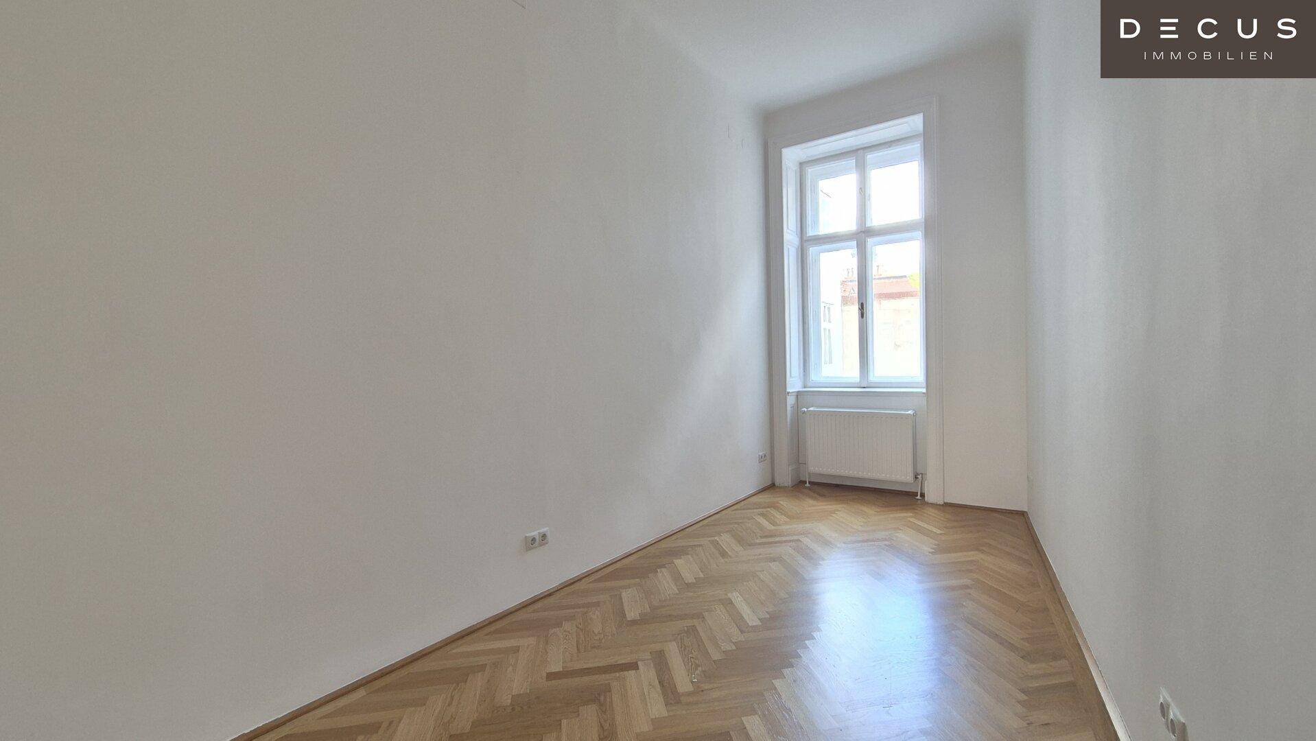 Helles Schlafzimmer mit Fischgrätparkett und großem Fenster, ideal für Ruhe.