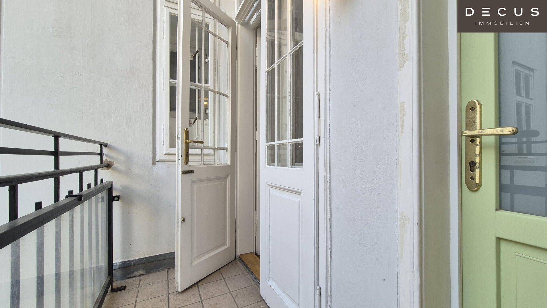 Zugang zum Balkon mit klassischen Flügeltüren und Blick auf den Innenhof.