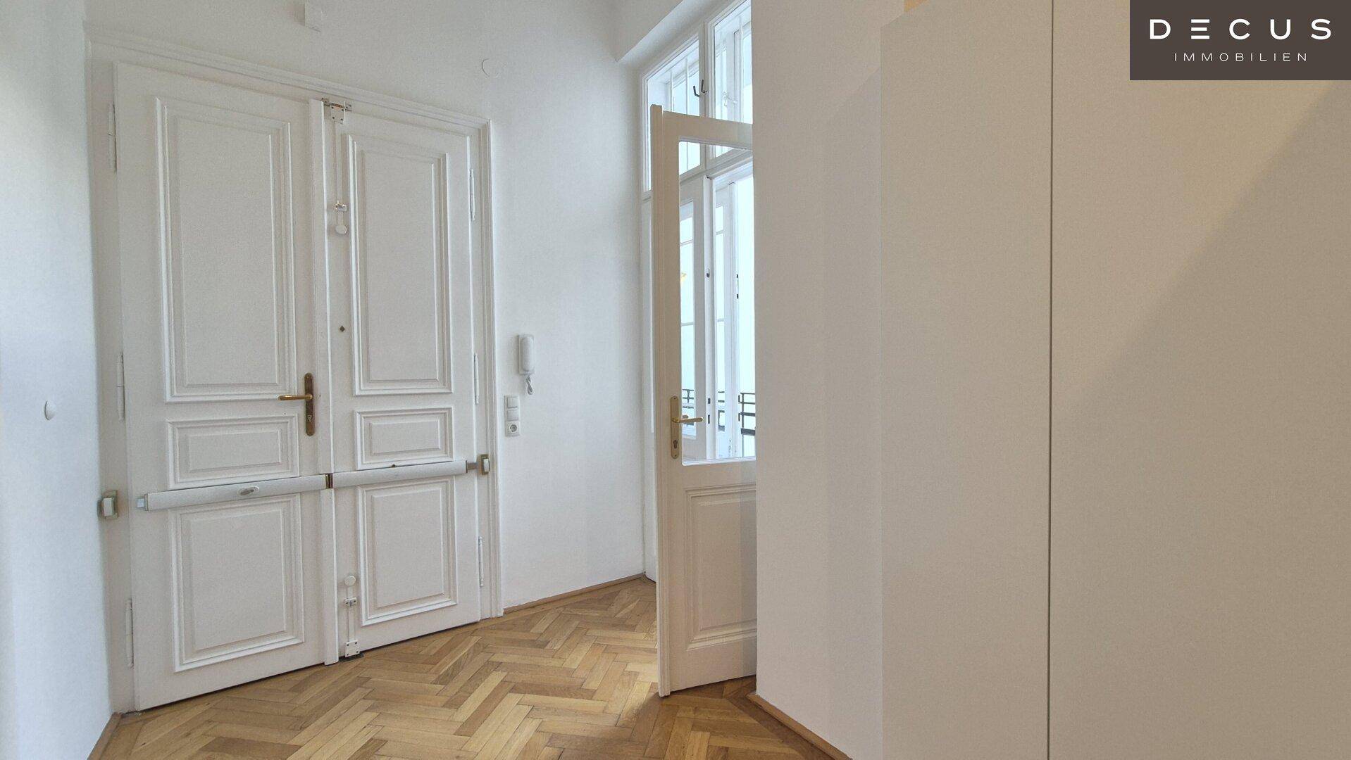 Heller Flur mit Fischgrätparkett, hohen Türen und Einbauschrank.