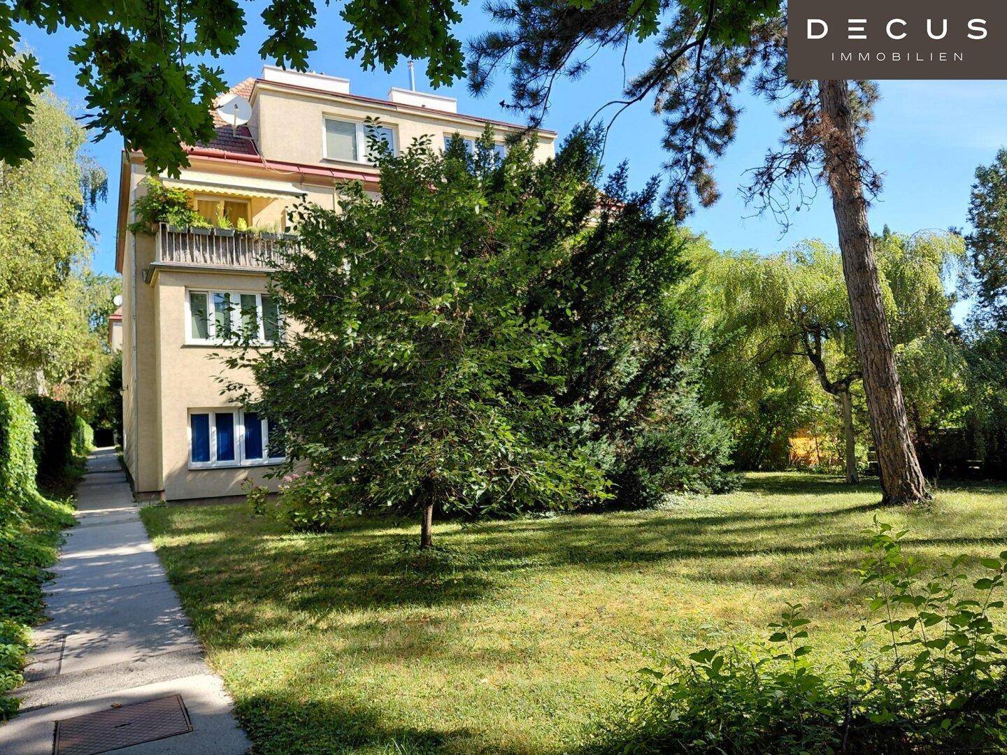 Außenansicht des Gebäudes mit einem Gehweg durch den grünen Gemeinschaftsgarten.