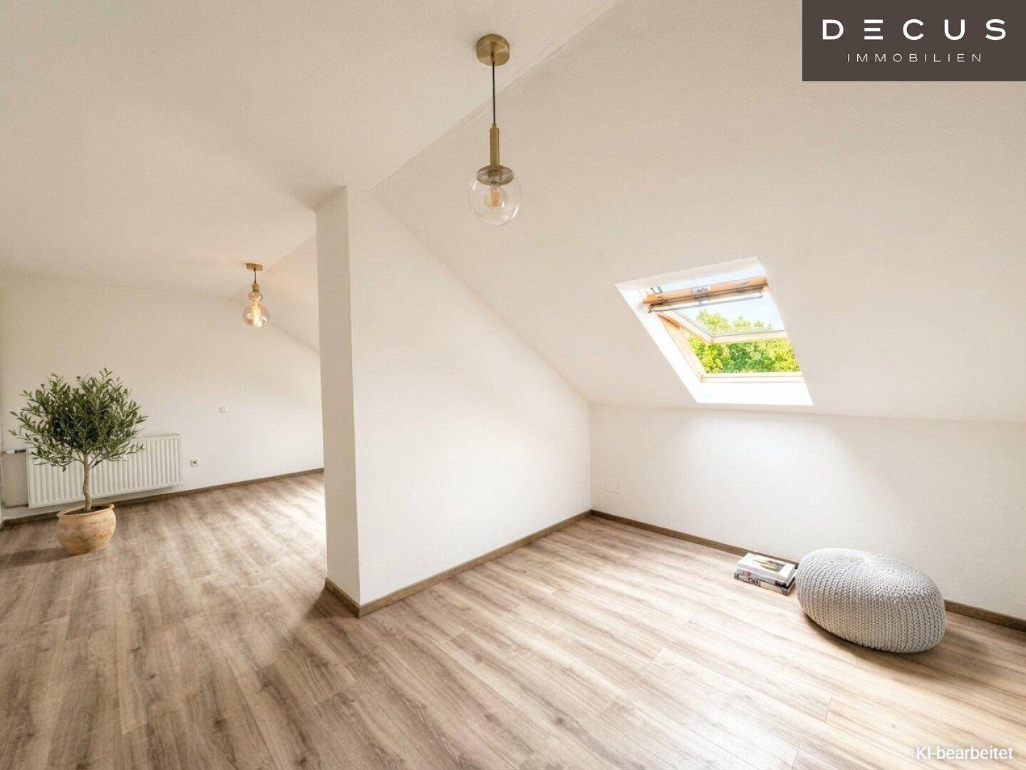 Geräumiger, heller Dachgeschossraum mit Laminatboden, Dachfenster und einem dekorativen Olivenbaum.