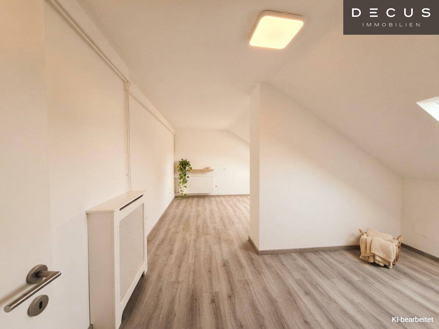 Heller Flurbereich im Dachgeschoss mit Laminatboden, Heizkörper und einem Dachfenster für natürliches Licht.