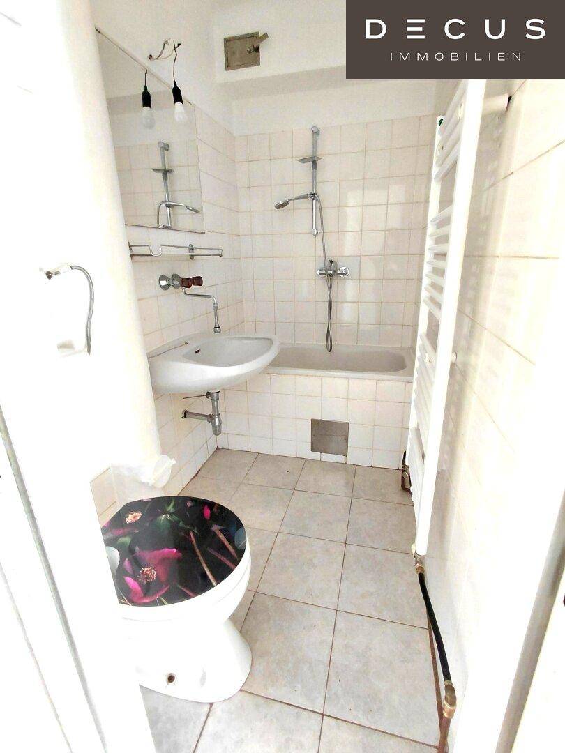 Gefliestes Badezimmer mit Badewanne, Dusche, Waschbecken und beheiztem Handtuchhalter.