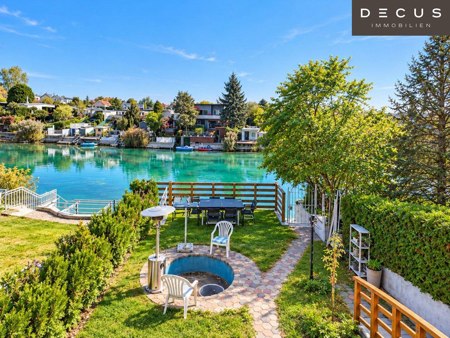 Sonniger Garten mit Essbereich im Freien und direktem Blick auf den See.