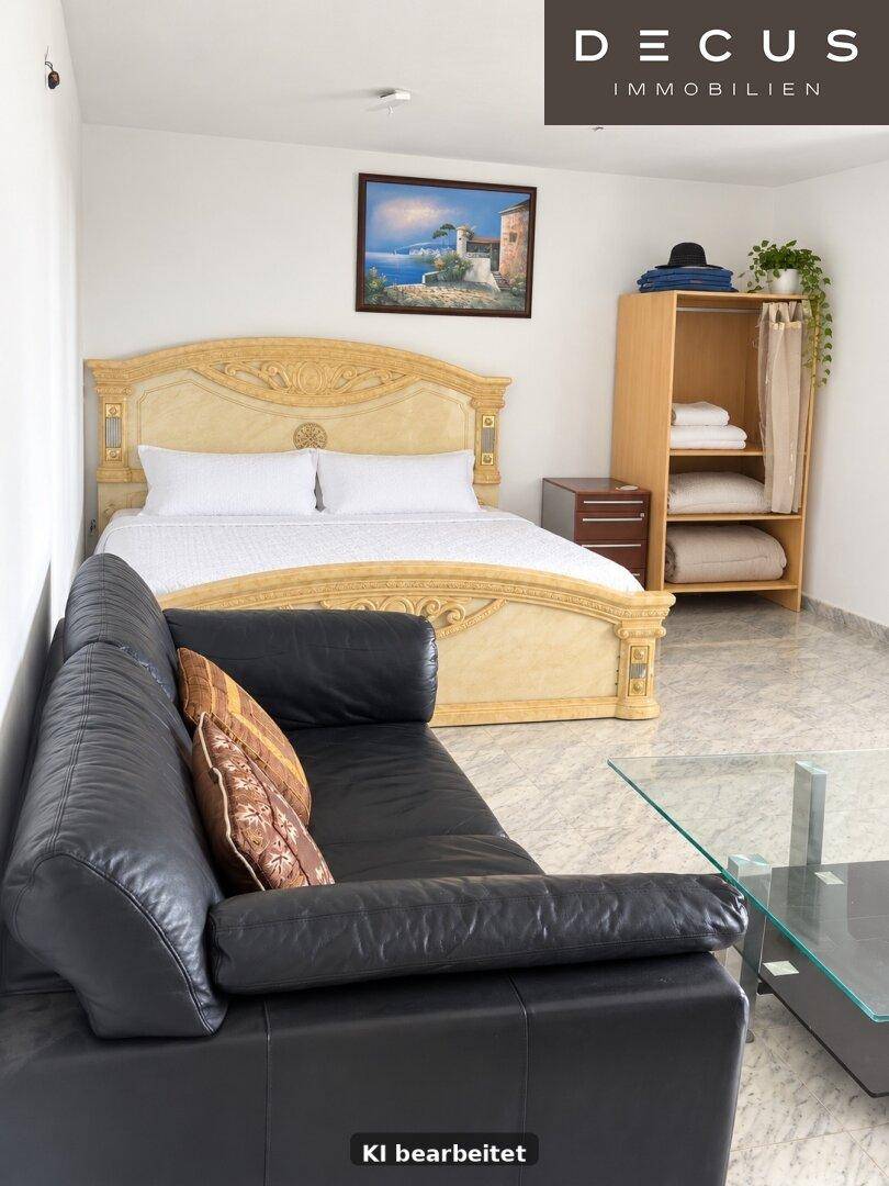 Schlafzimmer mit großem, verziertem Bett, Sofa und Fliesenboden, hell und freundlich.