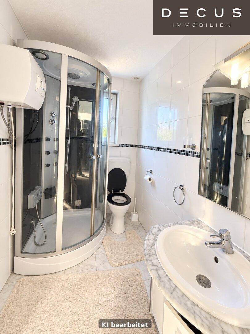 Modernes Badezimmer mit Duschkabine, weißen Fliesen und Marmorwaschtisch.