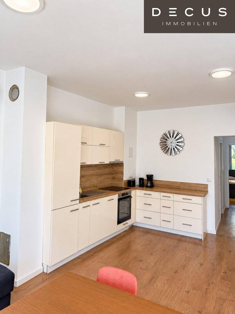 Moderne Einbauküche in hellem Design mit Holzarbeitsplatten und integrierten Geräten.