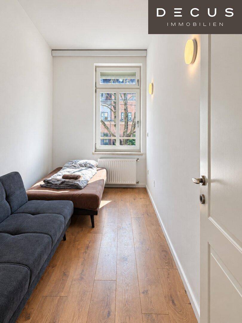 Kleines Zimmer mit Holzboden, Tagesbett und Fenster mit Blick auf die Umgebung.