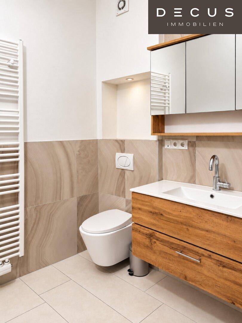 Stilvolles Badezimmer mit wandhängendem WC, Holzwaschtisch und beheiztem Handtuchhalter.