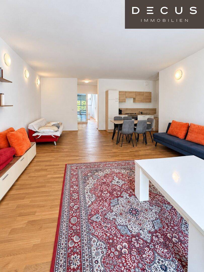 Offener Wohnbereich mit Holzboden, Essbereich und Blick auf die integrierte Küchenzeile.