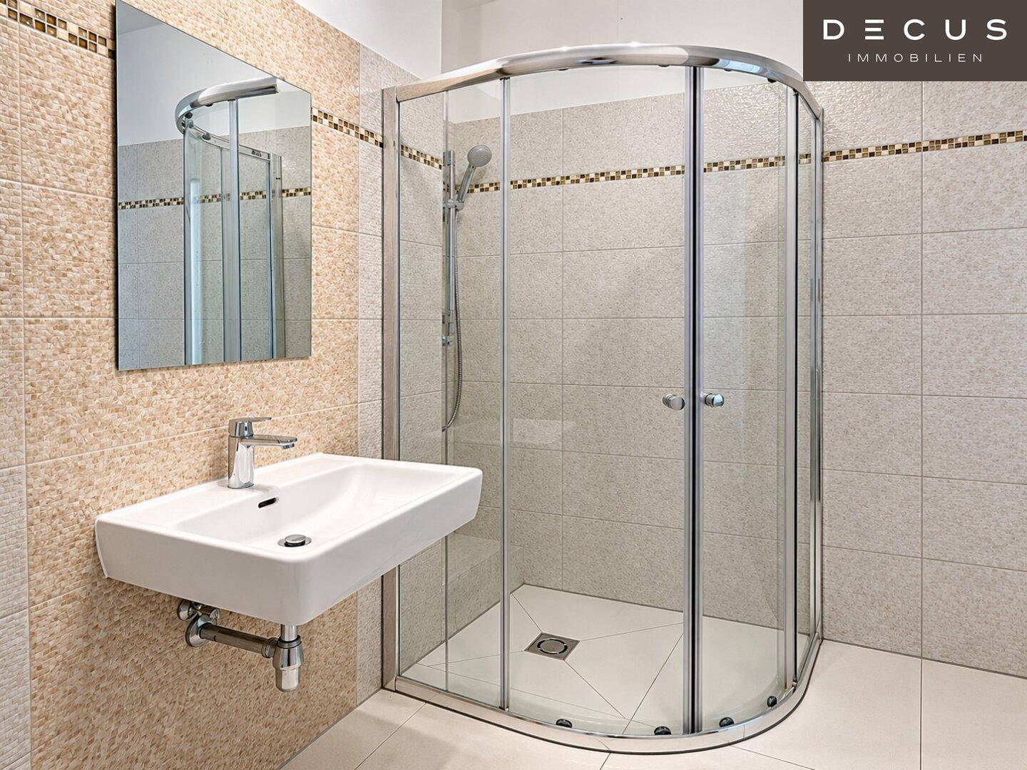 Modernes Badezimmer mit Duschkabine, Wandwaschbecken und hellen Fliesen an den Wänden.