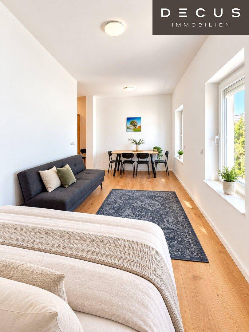 Helles Studio-Apartment mit Schlafbereich, Sofa, Esstisch und Laminatboden.