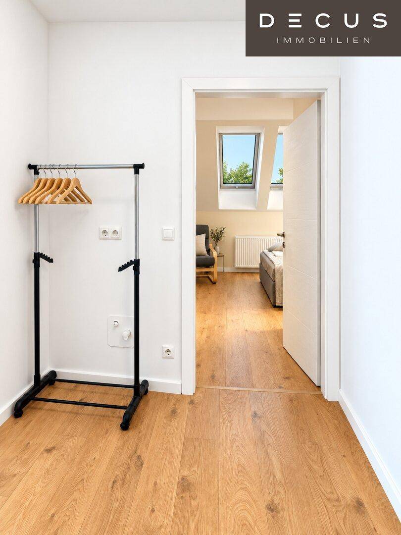 Heller Flur mit Garderobenständer und Zugang zu einem weiteren Zimmer im Dachgeschoss.