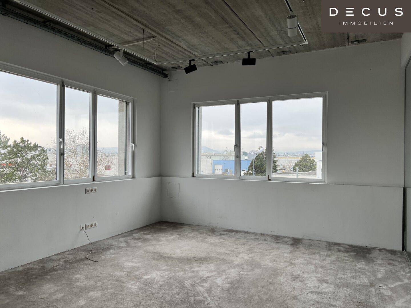 Leerer Büroraum mit mehreren Fenstern und Blick auf die Stadt.