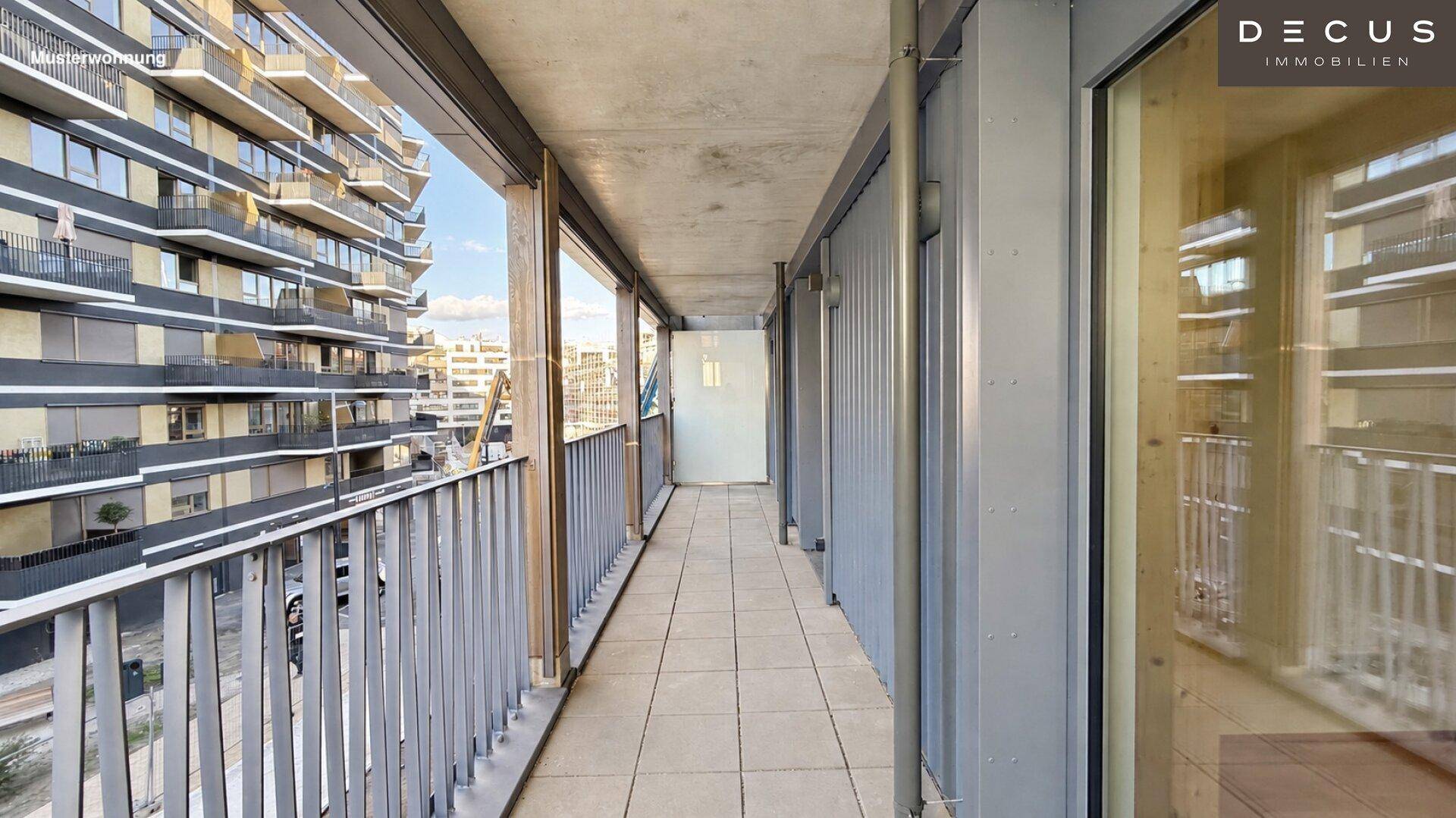 Langer Balkon mit Fliesenboden und Blick auf die umliegenden modernen Gebäude.