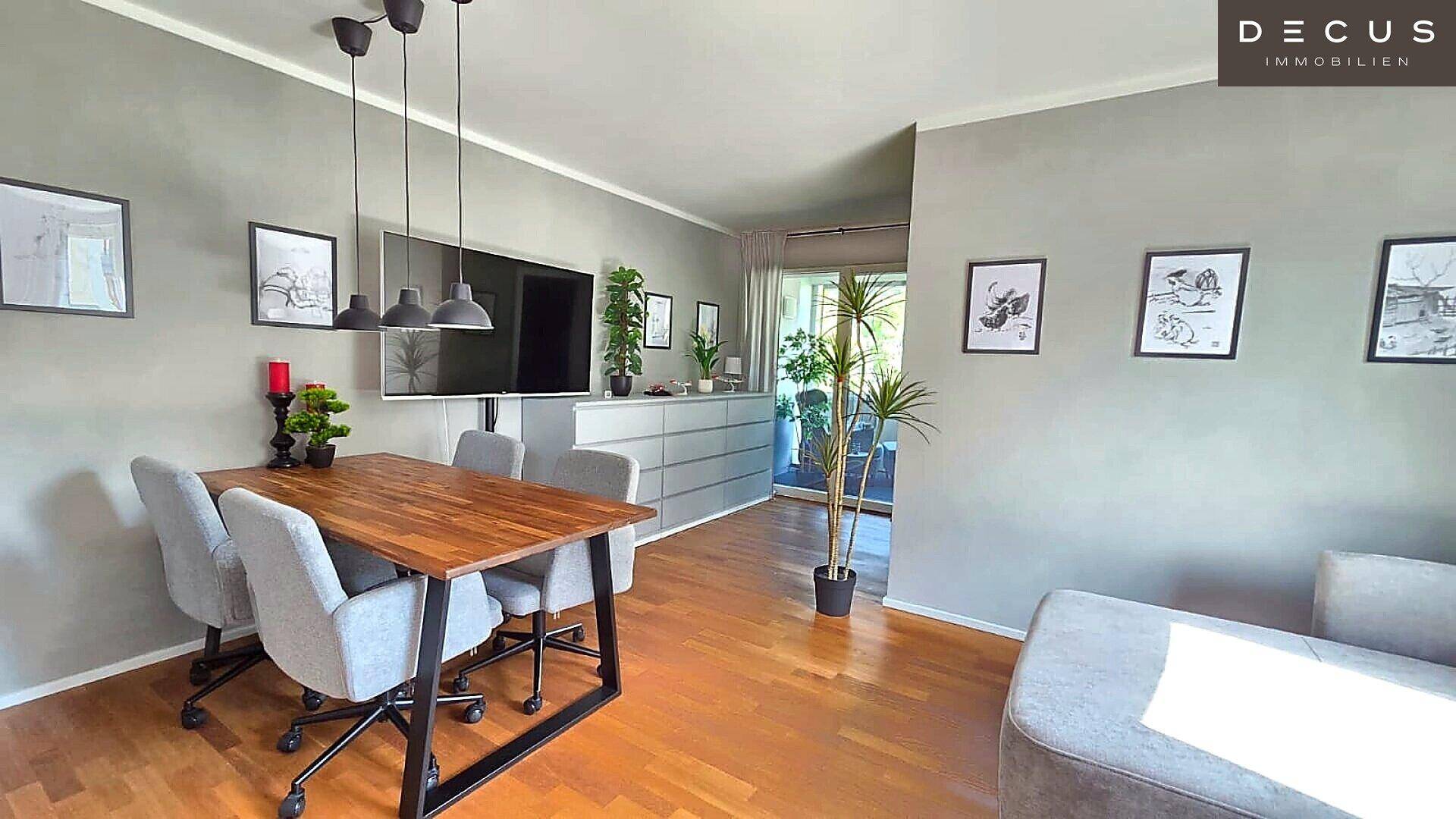 Moderner Wohn- und Essbereich mit Holzboden, großem Fernseher und Zugang zur Loggia.