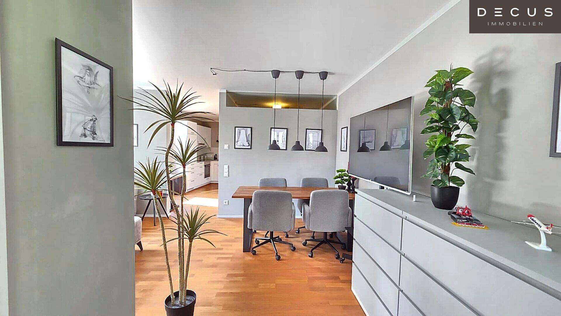 Offener Wohn- und Essbereich mit Holzboden und Blick auf die angrenzende moderne Küche.