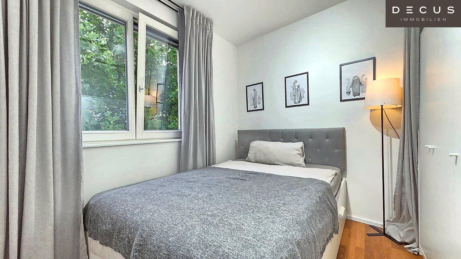 Helles Schlafzimmer mit Einzelbett, Holzboden und Blick auf Bäume.