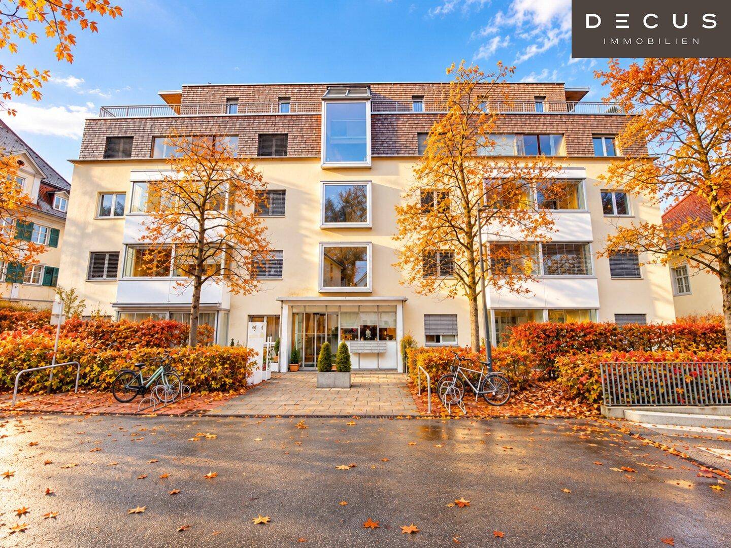 Attraktive Wohnfassade mit vielen Fenstern und herbstlicher Bepflanzung.