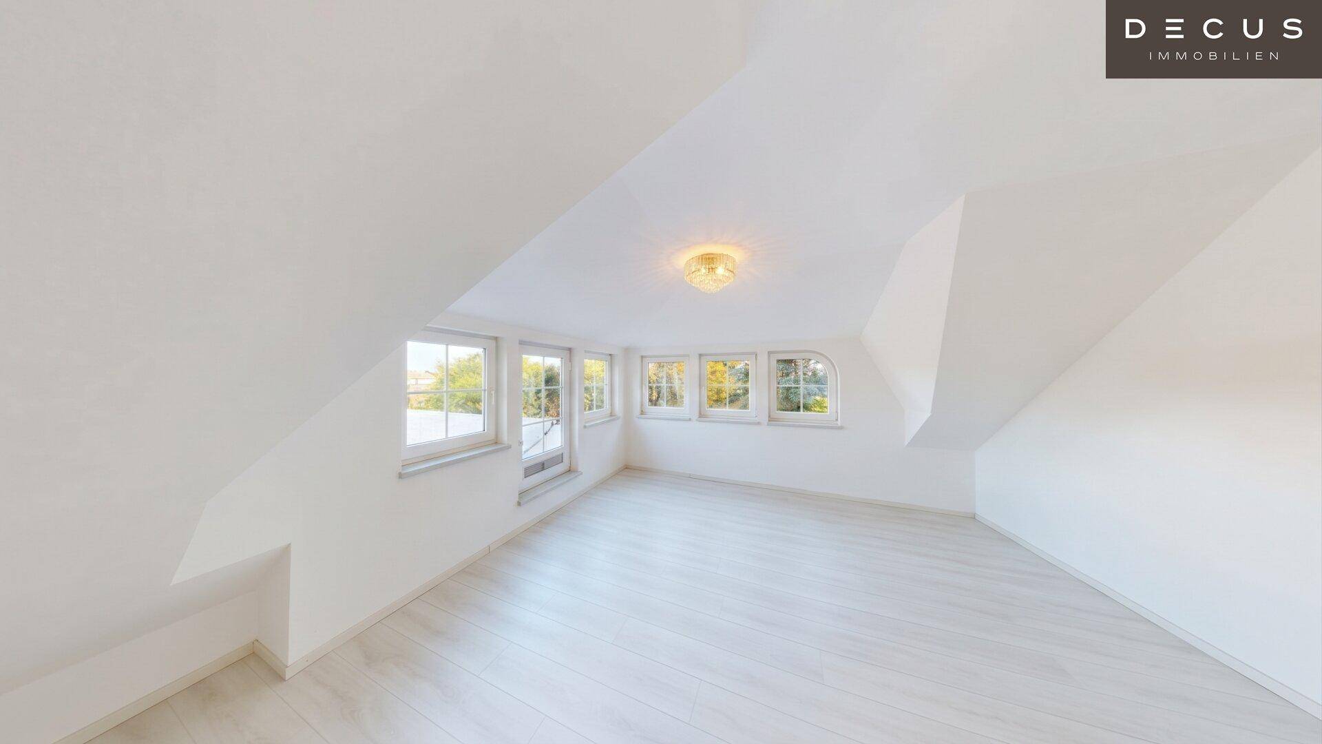 Helles Dachzimmer mit weißem Laminatboden und mehreren Fenstern, ideal als Schlafzimmer.