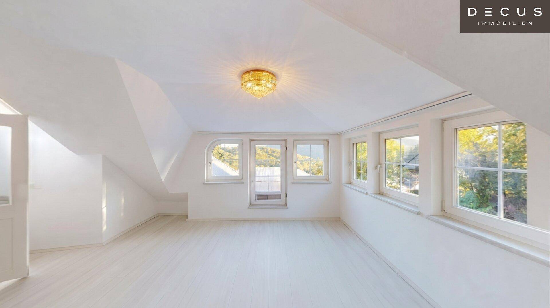 Geräumiges Dachzimmer mit Laminatboden und vielen Fenstern, die viel Tageslicht hereinlassen.