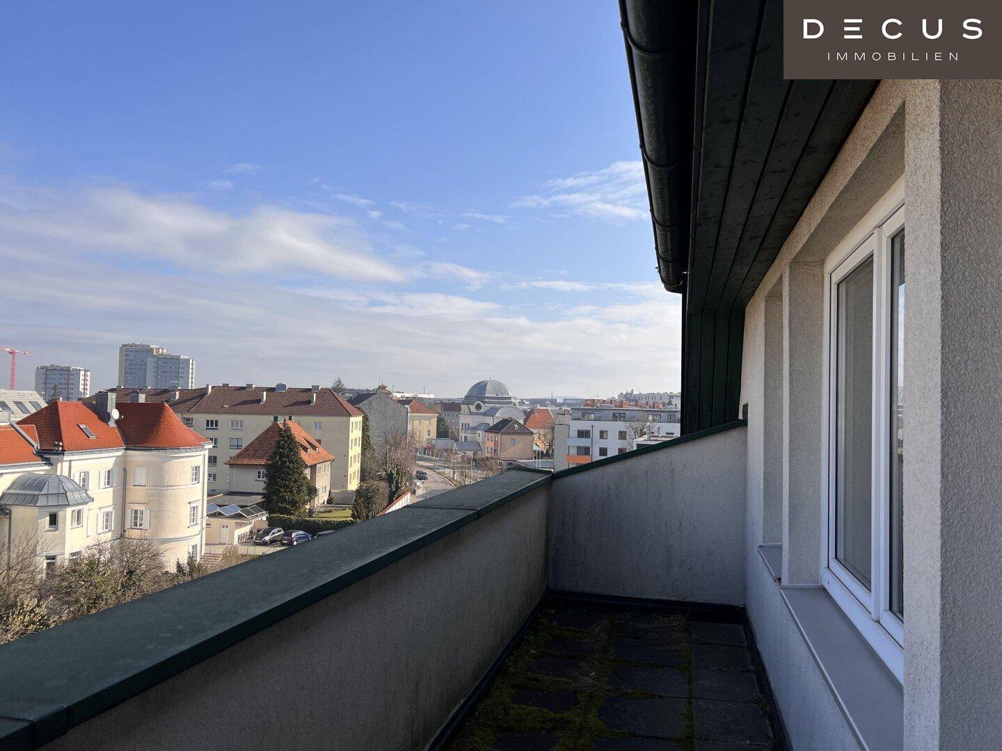 Kleiner Balkon mit Steinplattenboden und einer weiten Aussicht über die städtische Umgebung.