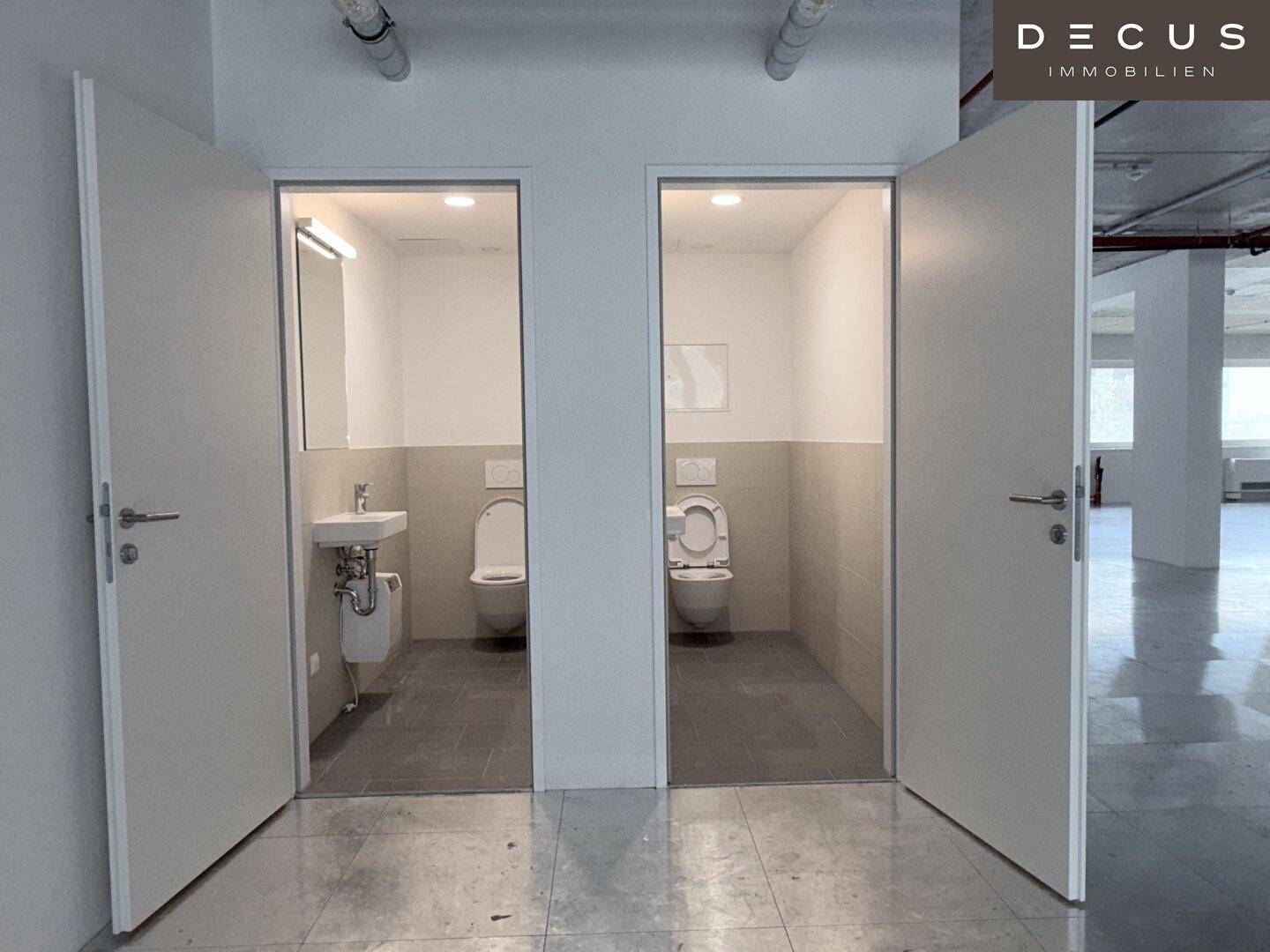 Zwei separate Toilettenräume mit modernen Sanitäreinrichtungen und halbhohen Fliesen an den Wänden.