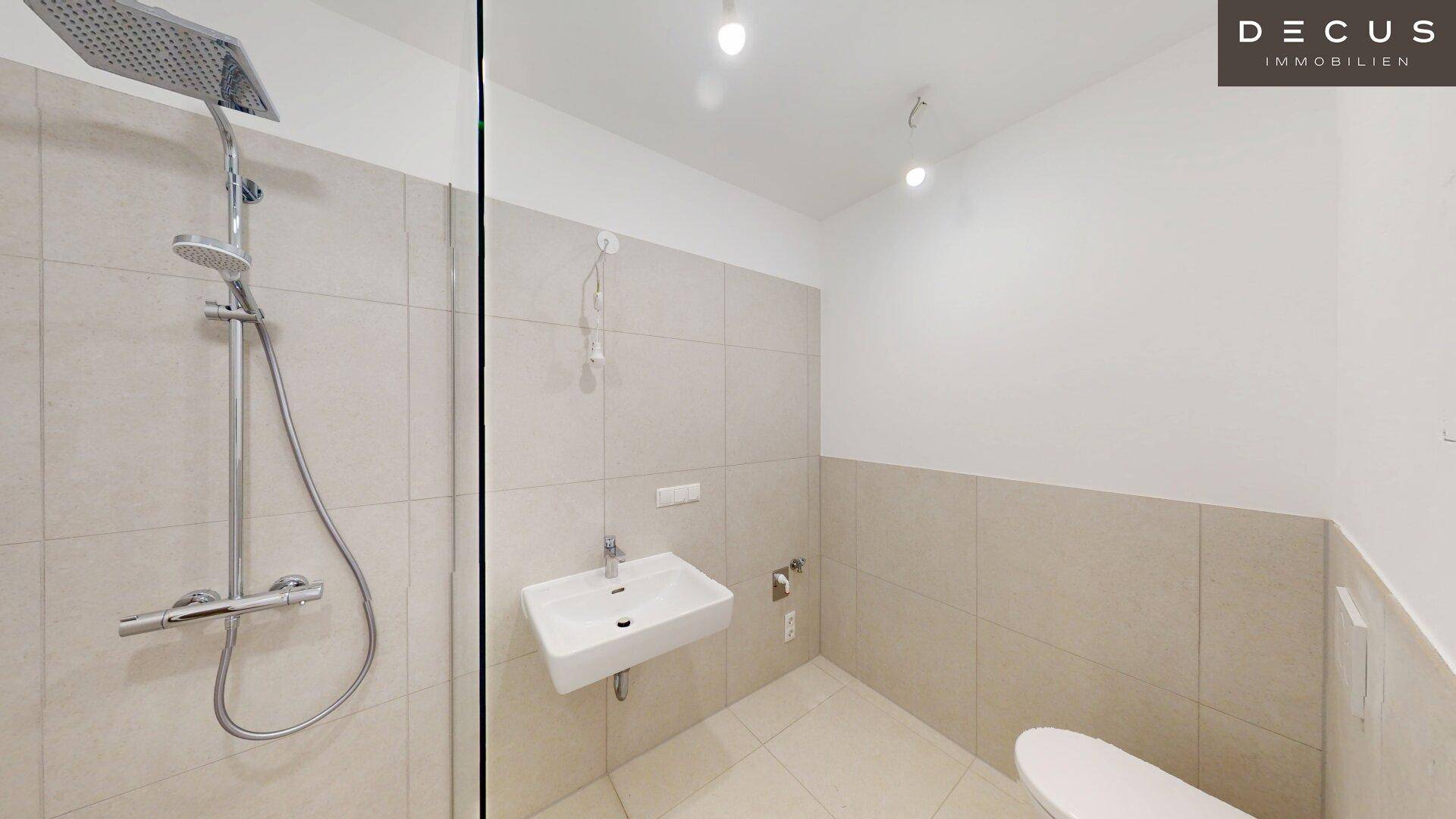 Modernes Badezimmer mit begehbarer Regendusche, Wand-WC und hellen, großformatigen Fliesen.