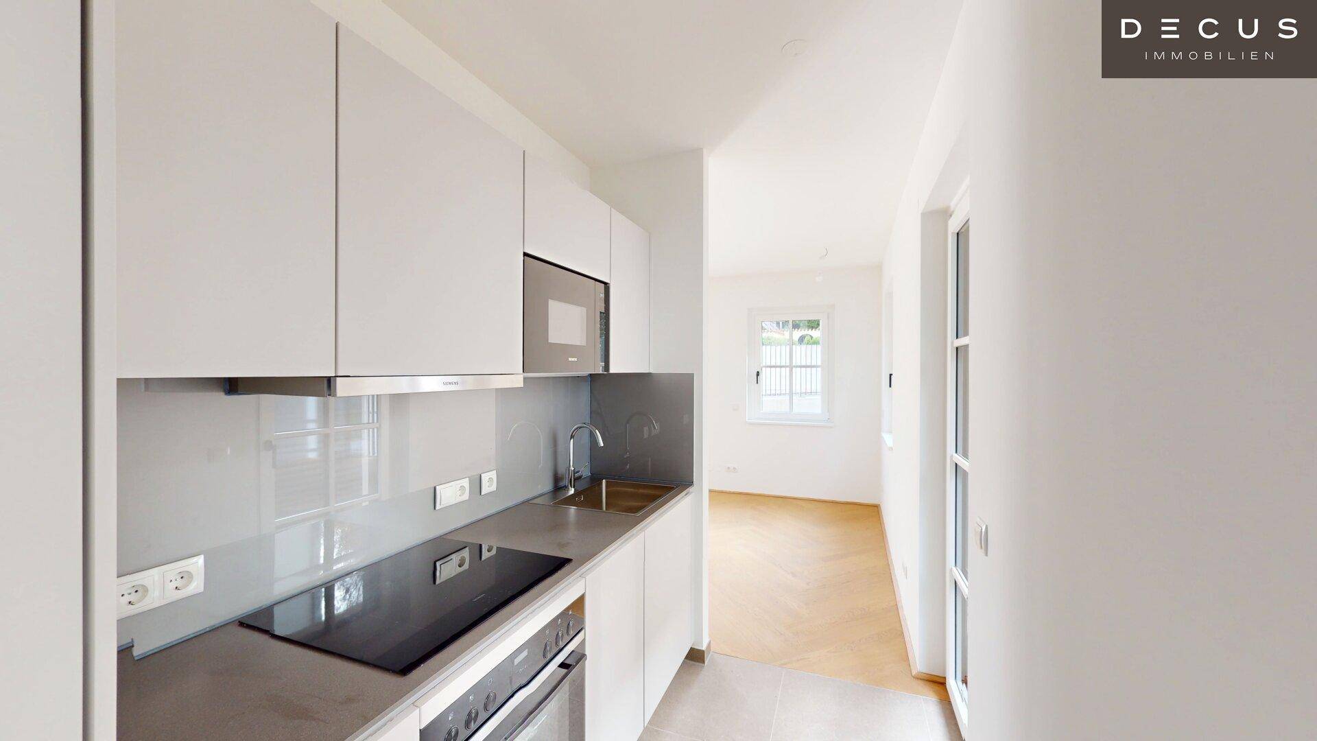 Moderne Einbauküche mit weißen Hochglanzfronten, Induktionskochfeld und integrierten Geräten.