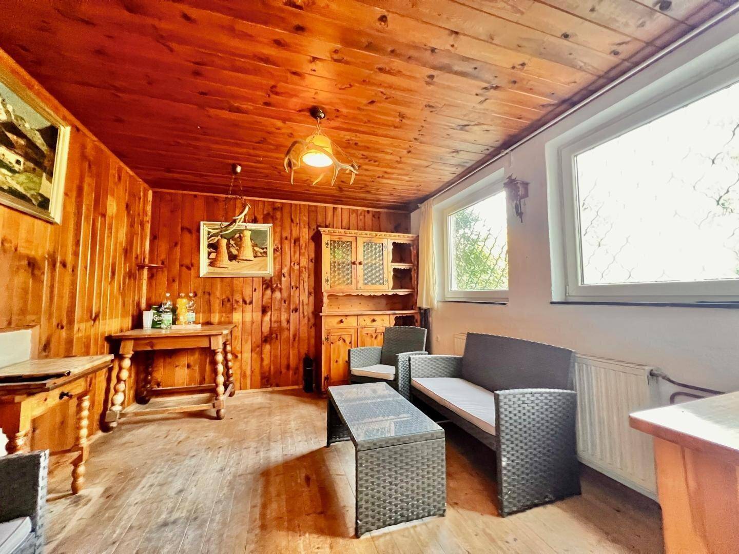 Rustikales Wohnzimmer mit Holzvertäfelung an Wänden und Decke sowie traditionellen Möbeln und Dekorationen.