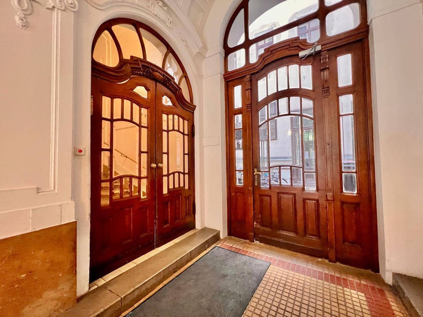 Zwei kunstvoll geschnitzte Holztüren im Eingangsbereich eines historischen Gebäudes mit Oberlichtern.