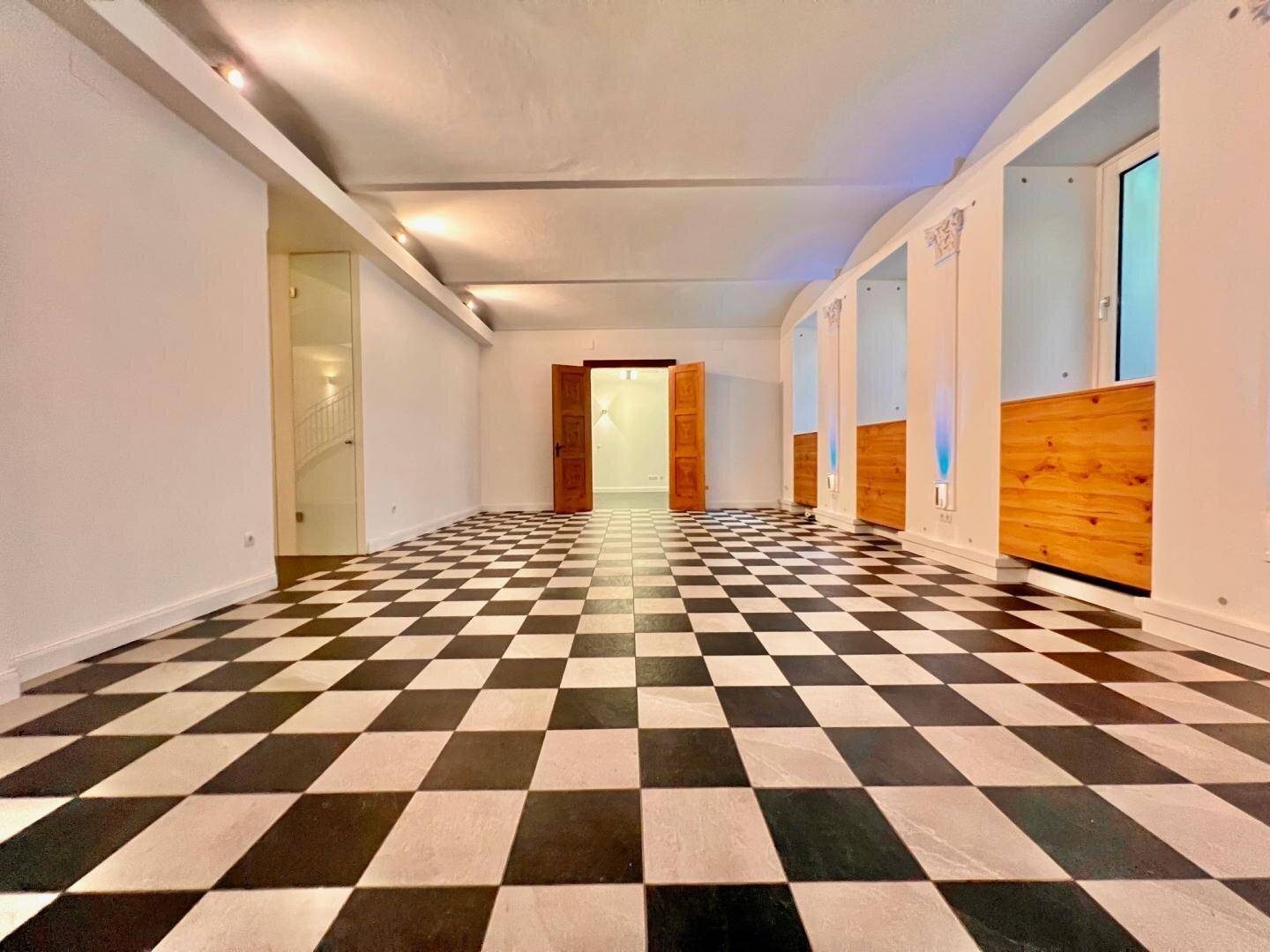 Großer, leerer Raum mit markantem schwarz-weißem Schachbrettmuster-Fliesenboden und gewölbter Decke.