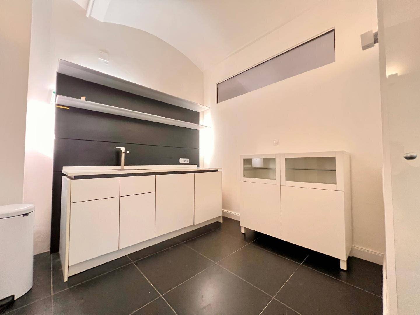 Kompakte Küchenzeile mit minimalistischem Design, weißen Unterschränken und integriertem Spülbecken.