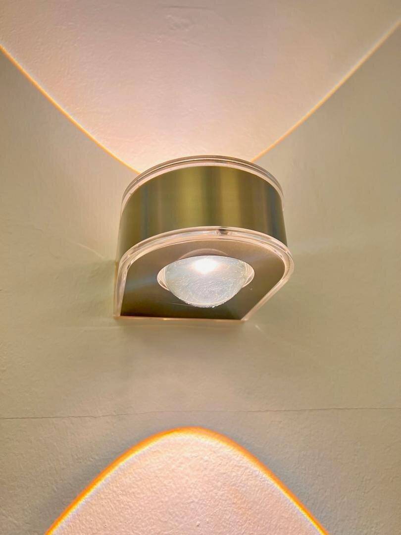 Moderne Wandleuchte mit indirekter Beleuchtung, die ein warmes Licht an die Wand wirft.