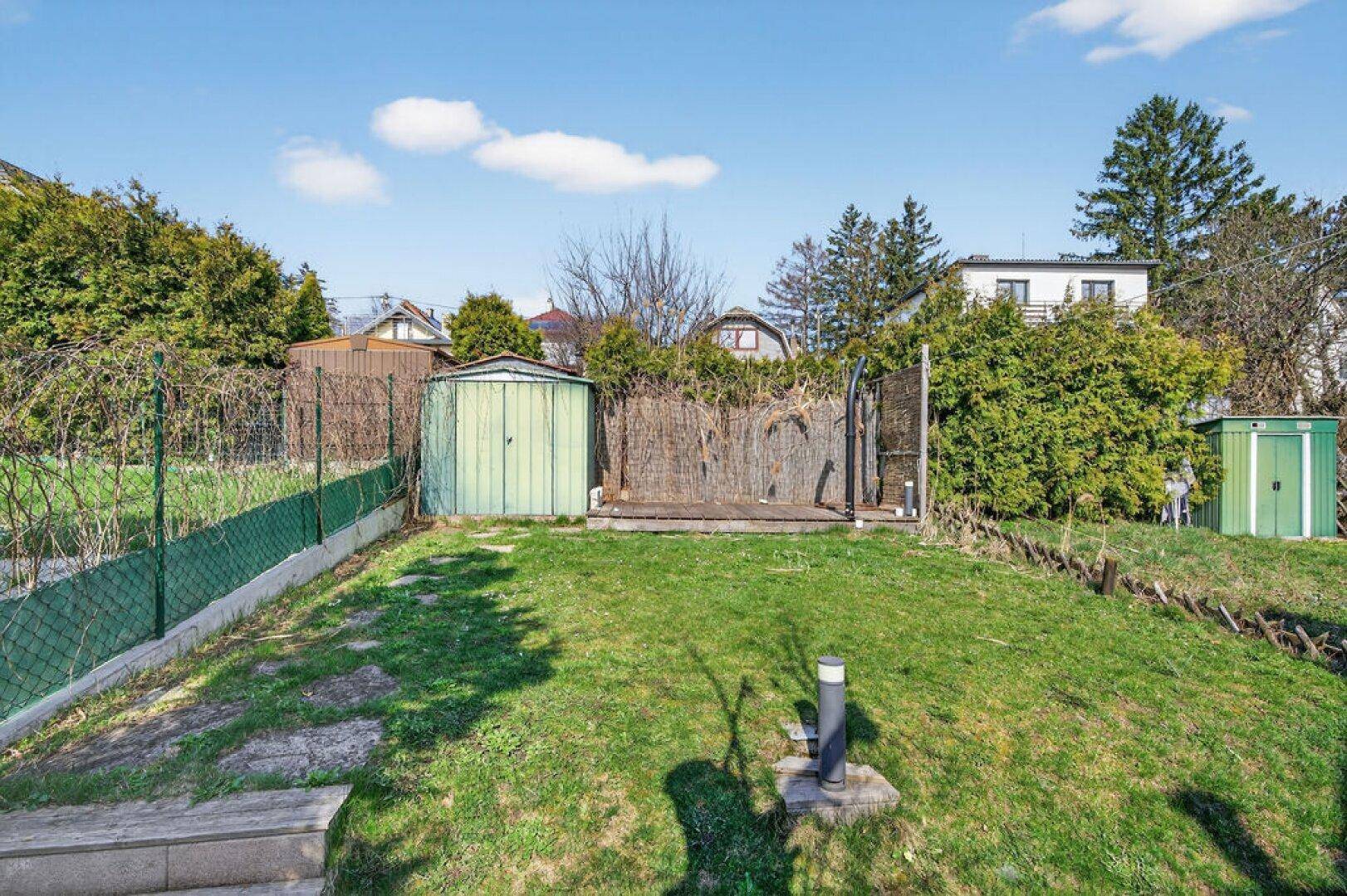 Gepflegter Gartenbereich mit Rasenfläche, Gartenhäuschen und Hecken.