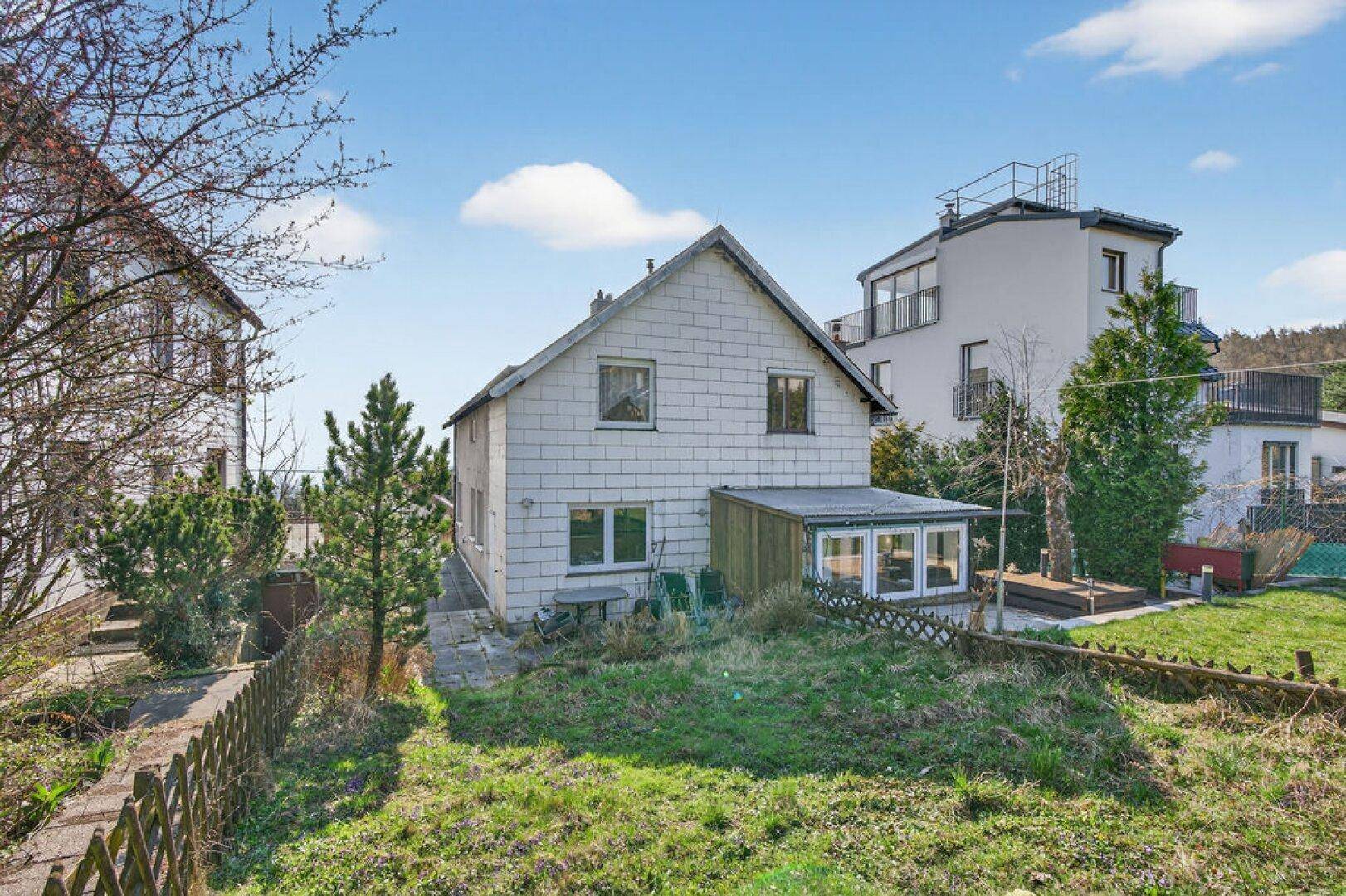 Hausrückseite mit großem Garten, Terrasse und Blick auf die umliegende Natur.
