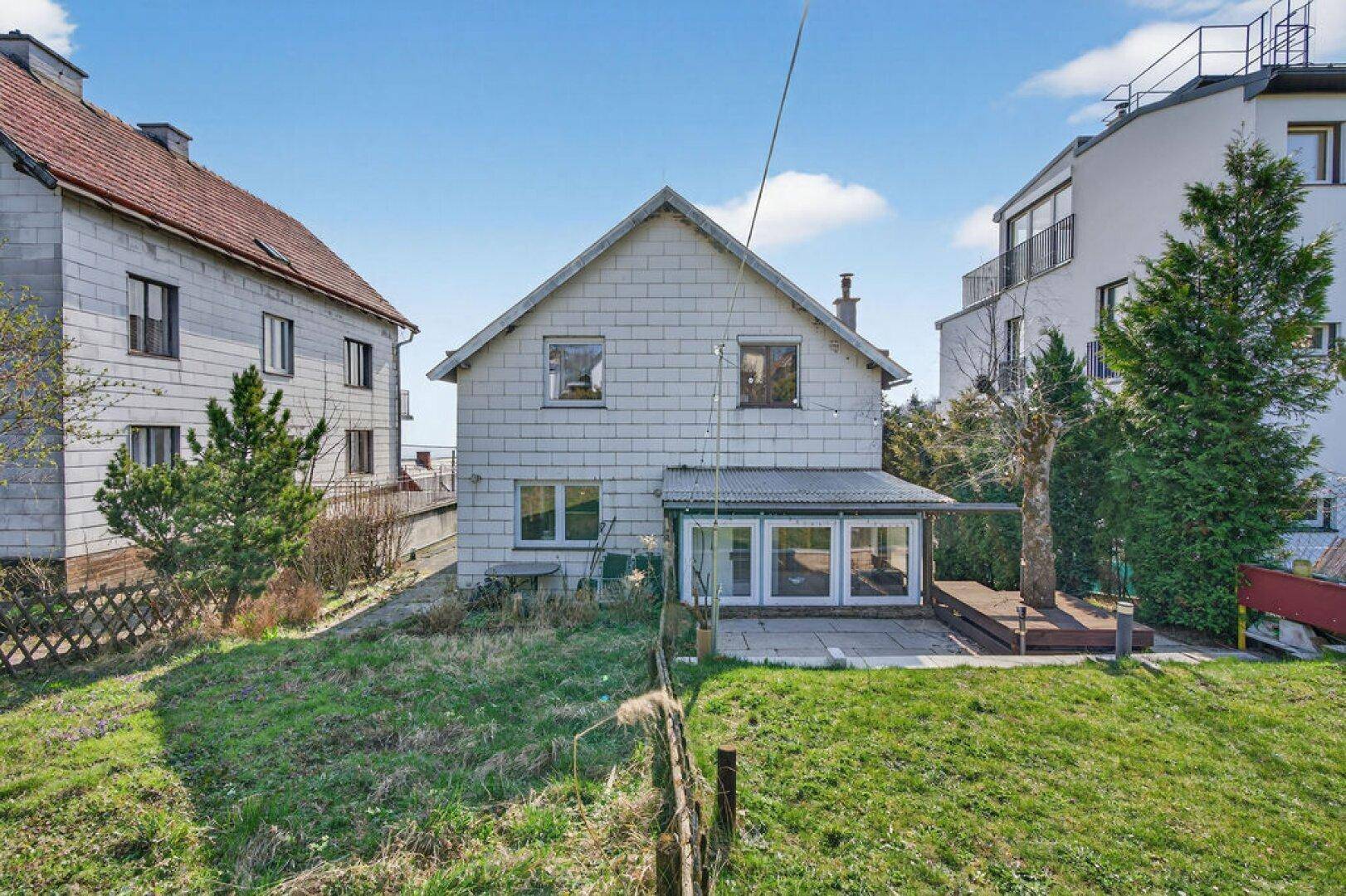 Rückansicht des Hauses mit weitläufigem Garten, Terrasse und Holzdeck.