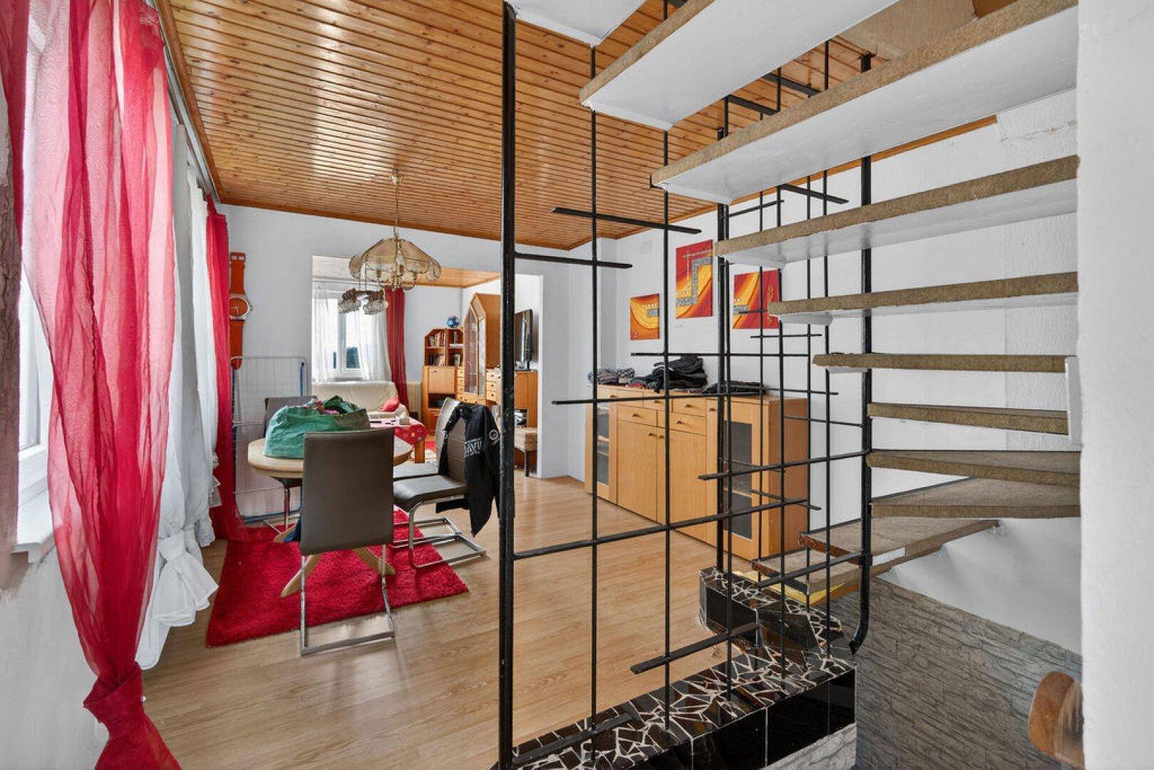 Offener Wohnbereich mit Treppe, Holzboden und farbenfroher Dekoration.
