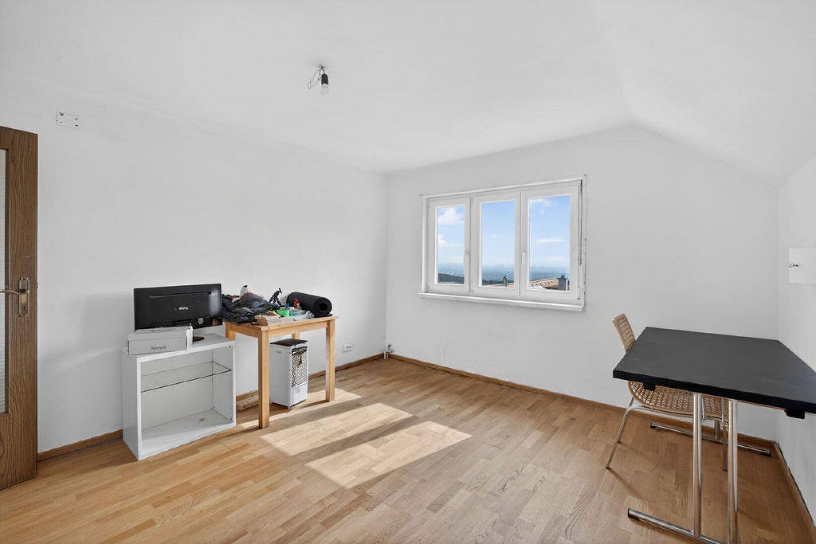 Helles Zimmer mit Holzboden, Dachschräge und weitem Ausblick.