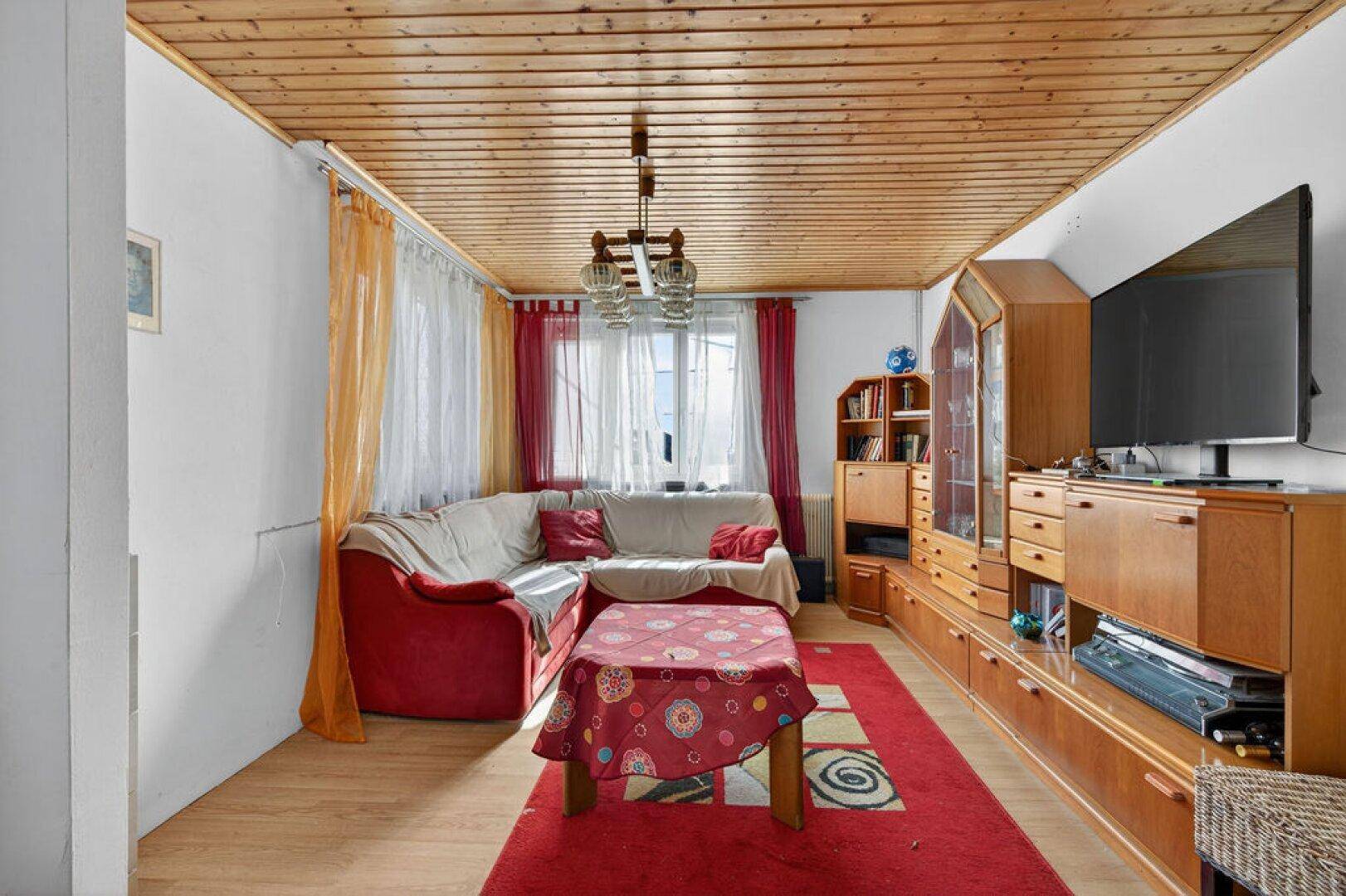 Gemütliches Wohnzimmer mit Ecksofa, Holzdecke und traditionellen Möbeln.