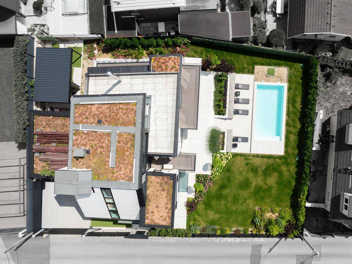 Luftaufnahme des Anwesens mit modernem Haus, begrünten Dächern, Pool und weitläufigem Gartenbereich.