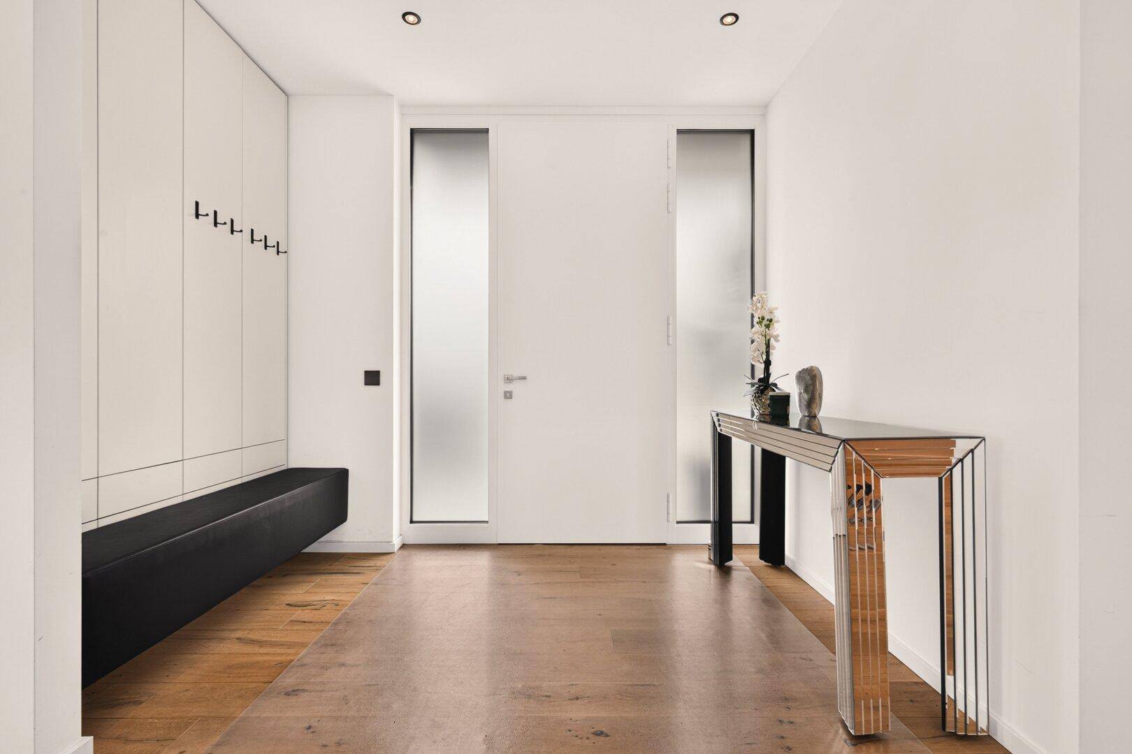 Heller Eingangsbereich mit Holzboden, integrierten Schränken und einer modernen Konsole.