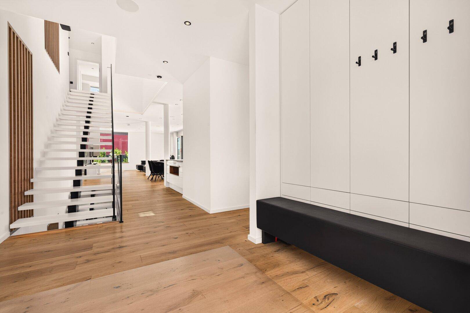 Geräumiger Flur mit Holzboden, Einbauschränken und einer eleganten Treppe, die in die oberen Etagen führt.